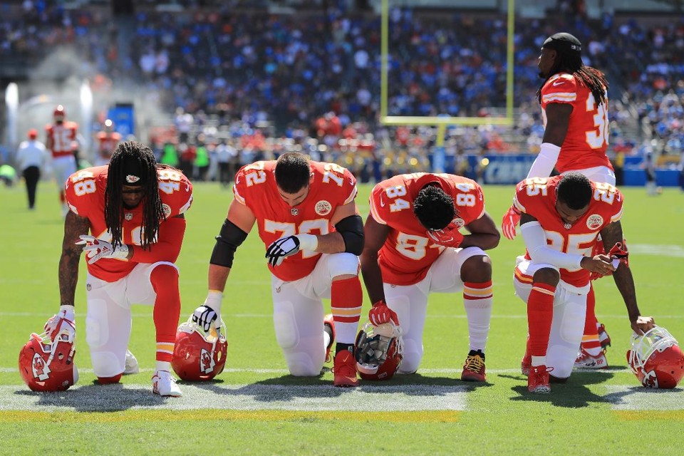Terrance Smith # 48, Eric Fisher # 72, Demetrius Harris # 84 e Cameron Erving # 75, dos Kansas City Chiefs, são vistos se ajoelhando antes do jogo contra os Los Angeles Charges no StubHub Center, em 24 de setembro de 2017, em Carson, Califórnia | Sean M. Haffey/AFP