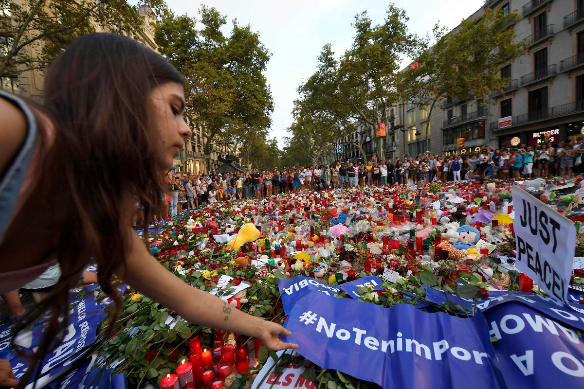 Mulher presta homenagem às vítimas dos ataques terroristas em Barcelona e Cambris | LLUIS GENE/AFP