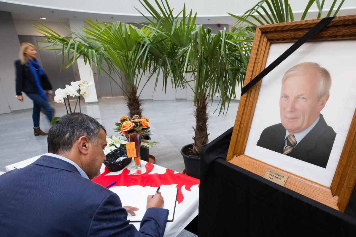 Homem escreve em livro de condolências, ao lado de um retrato de Alfred Gadenne | BENOIT DOPPAGNE/AFP