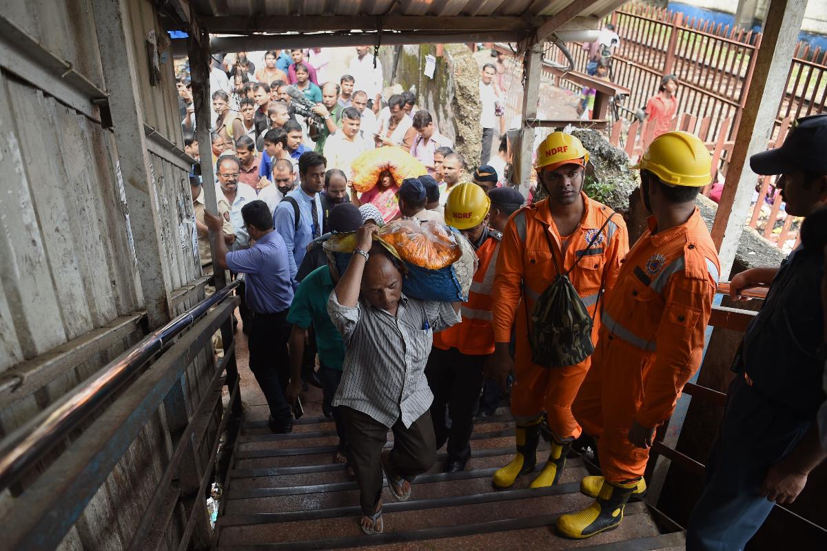 Socorristas indianos atravessam parte de ponte onde ocorreu tumulto com vítimas em Mumbai | PUNIT PARANJPE/AFP