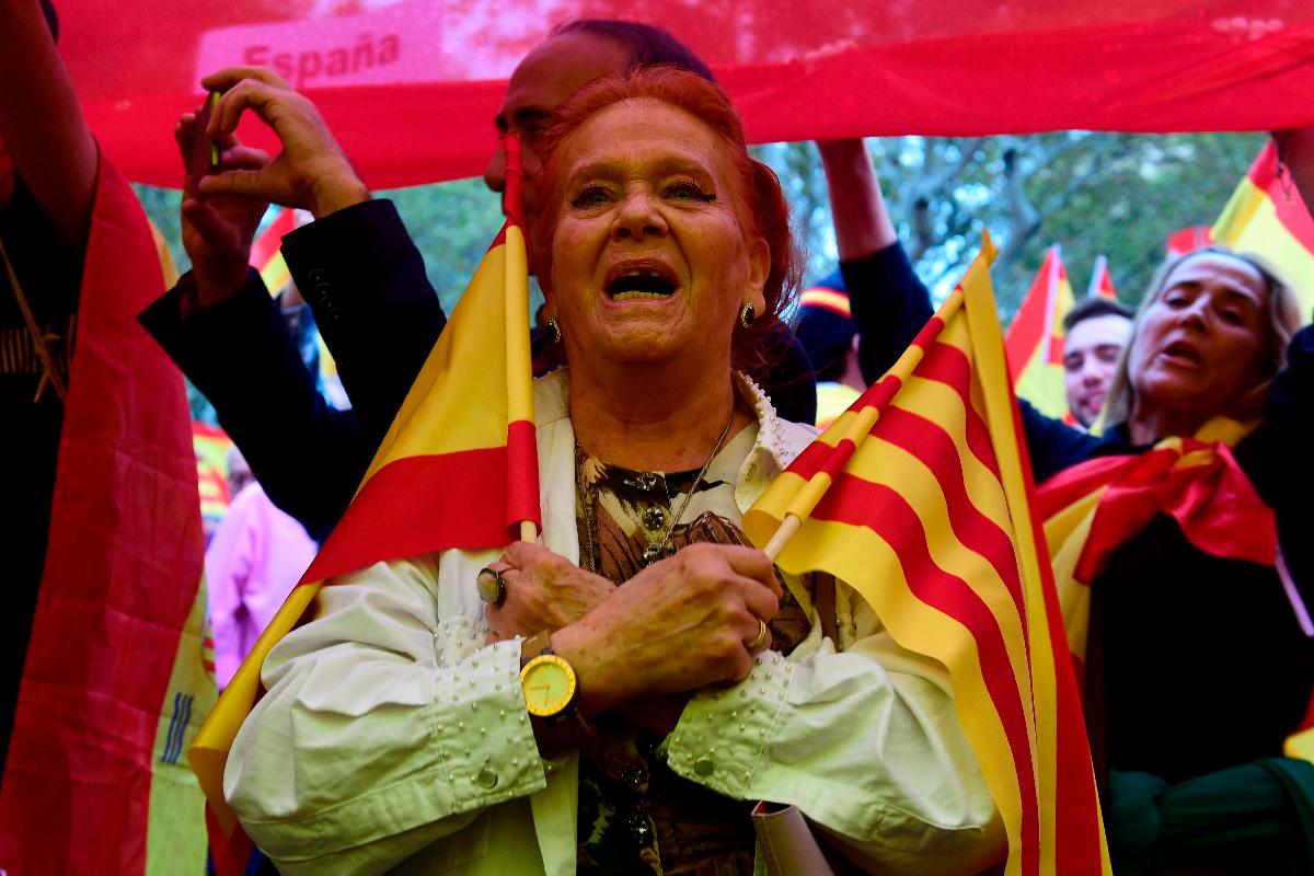 Uma mulher detém uma bandeira espanhola e catalã durante uma manifestação contra a independência na Catalunha, um dia antes do referendo | PIERRE-PHILIPPE MARCOU/AFP