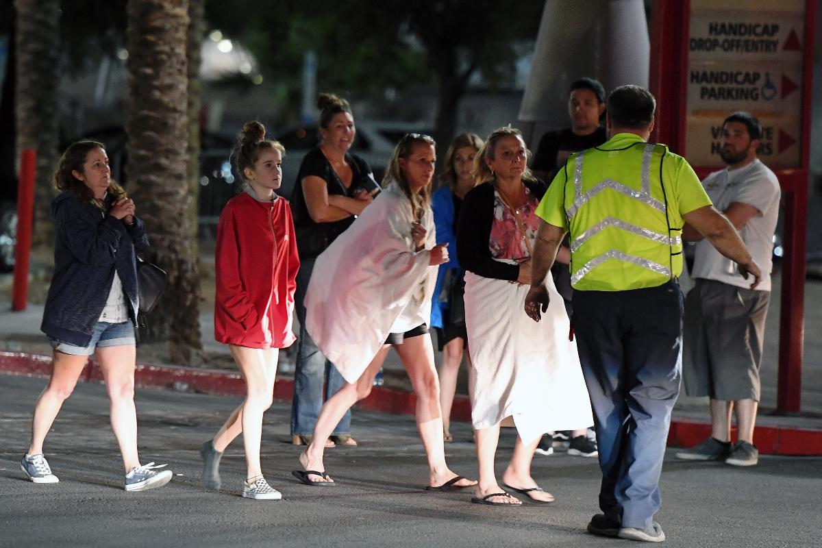 Pessoas são encaminhadas para fora do Thomas & Mack Center depois do tiroteio em um festival de música country em Las Vegas, Nevada. As pessoas que não podiam ir aos casinos do hotel que estavam fechados após o tiroteio ficaram temporariamente no centro | Ethan Miller/AFP