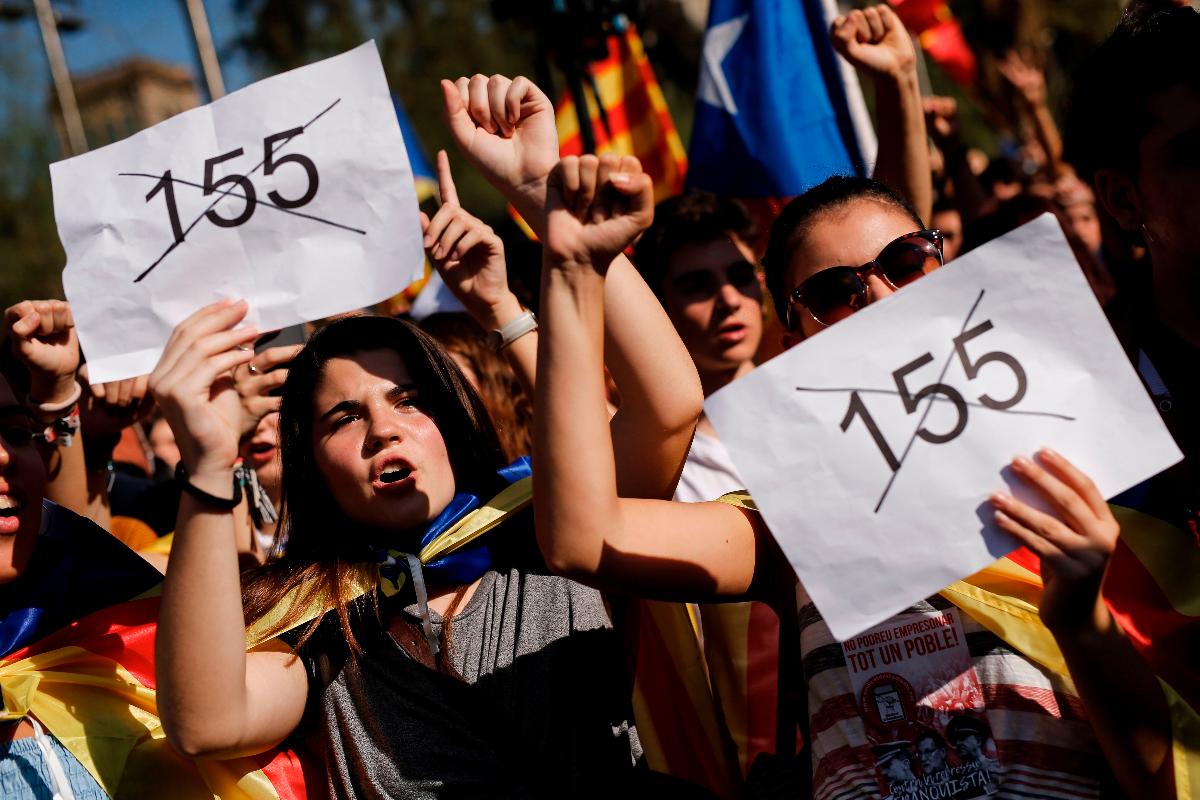 Manifestantes seguram cartazes contra o uso do Artigo 155 da Constituição da Espanha para retirar autonomia da Catalunha | PAU BARRENA/AFP