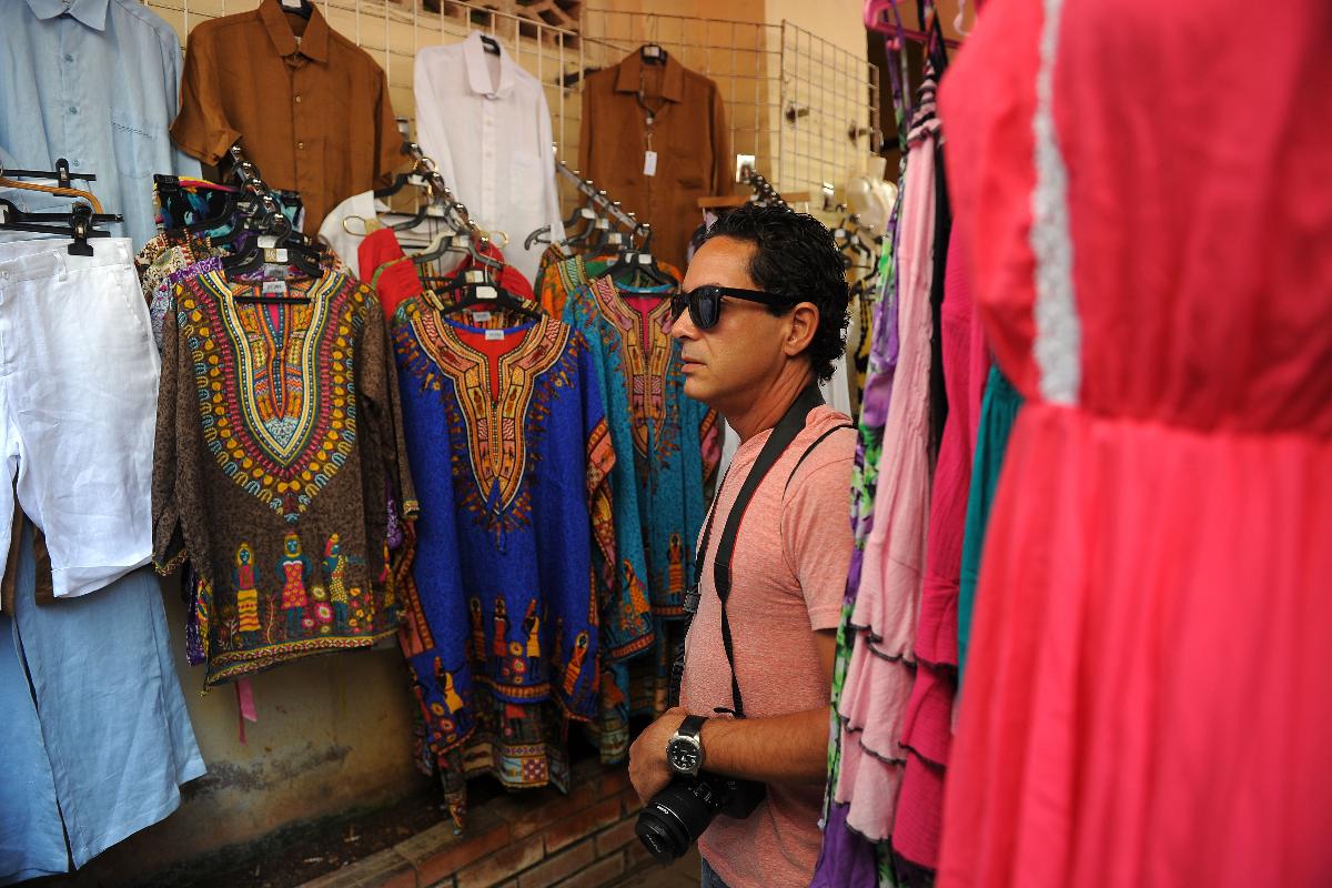 Um turista olha para roupas em uma loja de artesanato em Havana: comércio ainda precisa superar obstáculos burocráticos | YAMIL LAGE/AFP