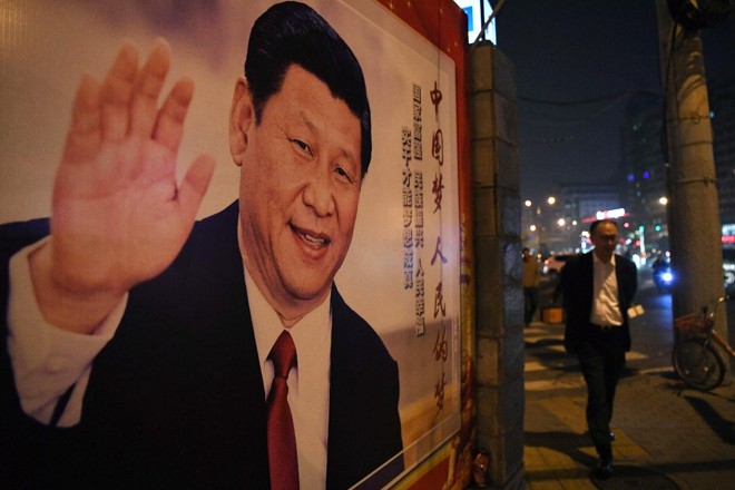 Homem passa por cartaz do presidente chinês Xi Jinping após o encerramento do 19º Congresso do Partido Comunista em Pequim. | GREG BAKER/AFP