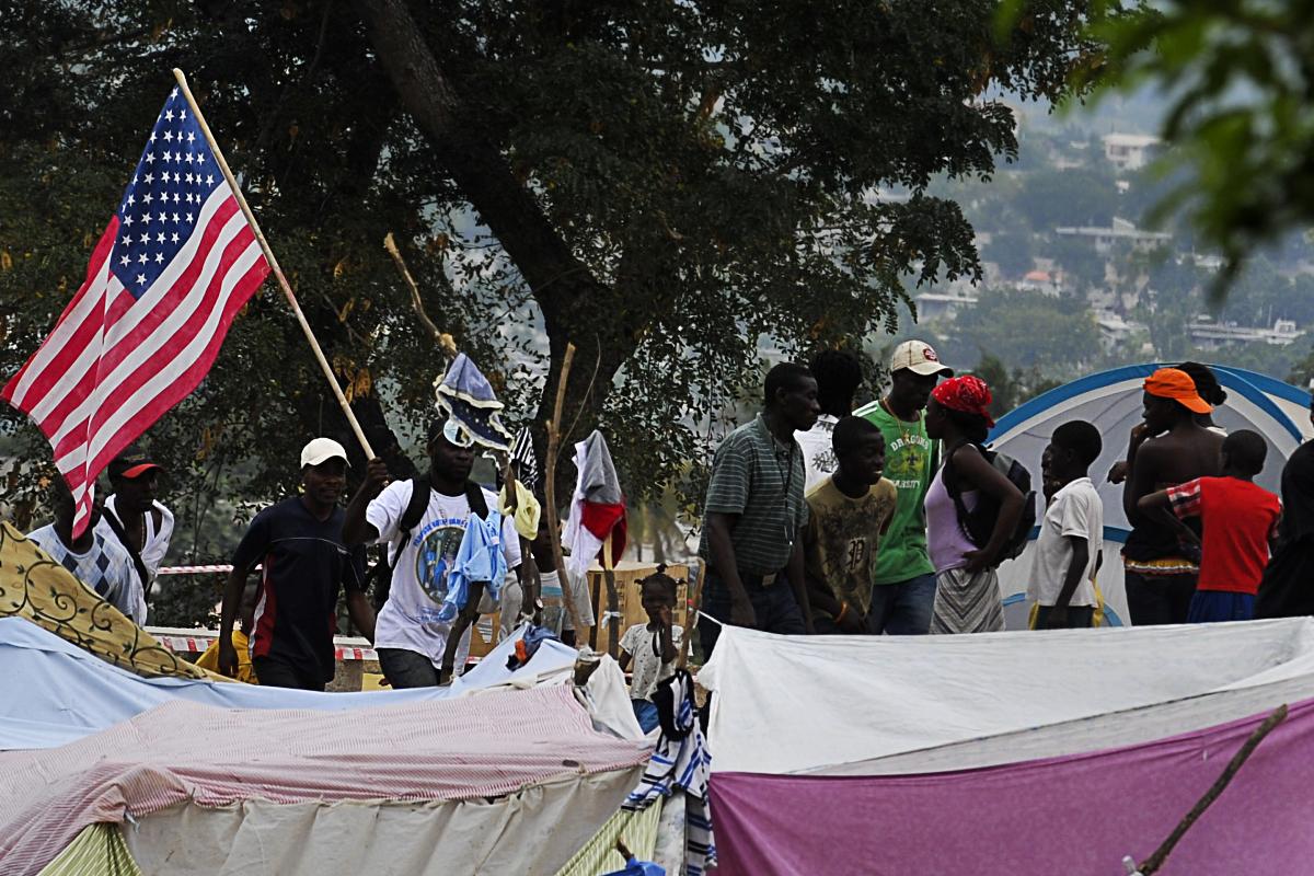 Haitianos carregam bandeira norte-americana no meio de um campo de refugiados, em Porto Príncipe, após o terremoto de 2010 | LA/dec/
LUIS ACOSTA