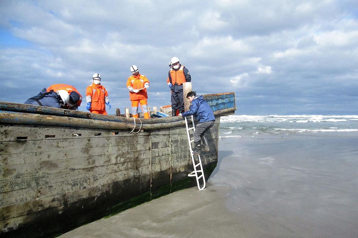 Oficiais da guarda costeira do Japão inspecionam um barco no qual oito corpos foram encontrados | AFP