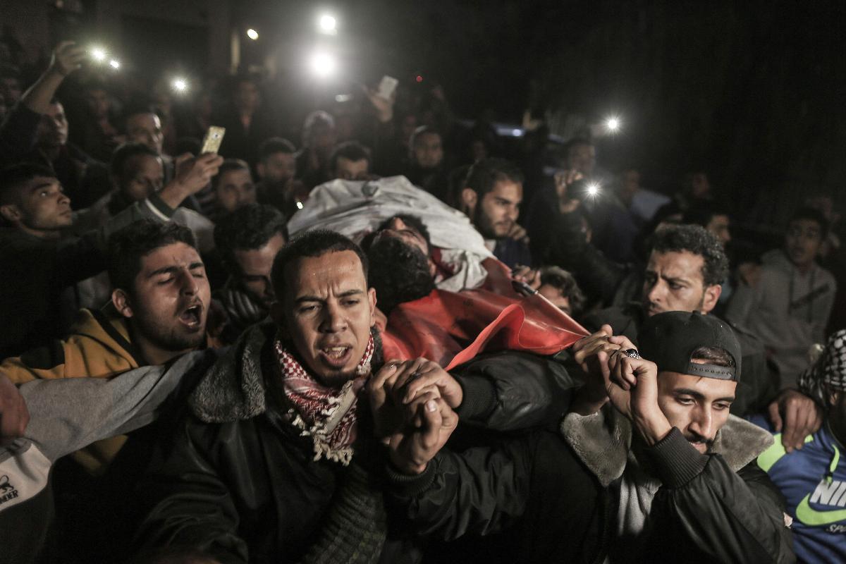 Palestinos carregam um homem que foi atingido durante os confrontos | MAHMUD HAMS/AFP