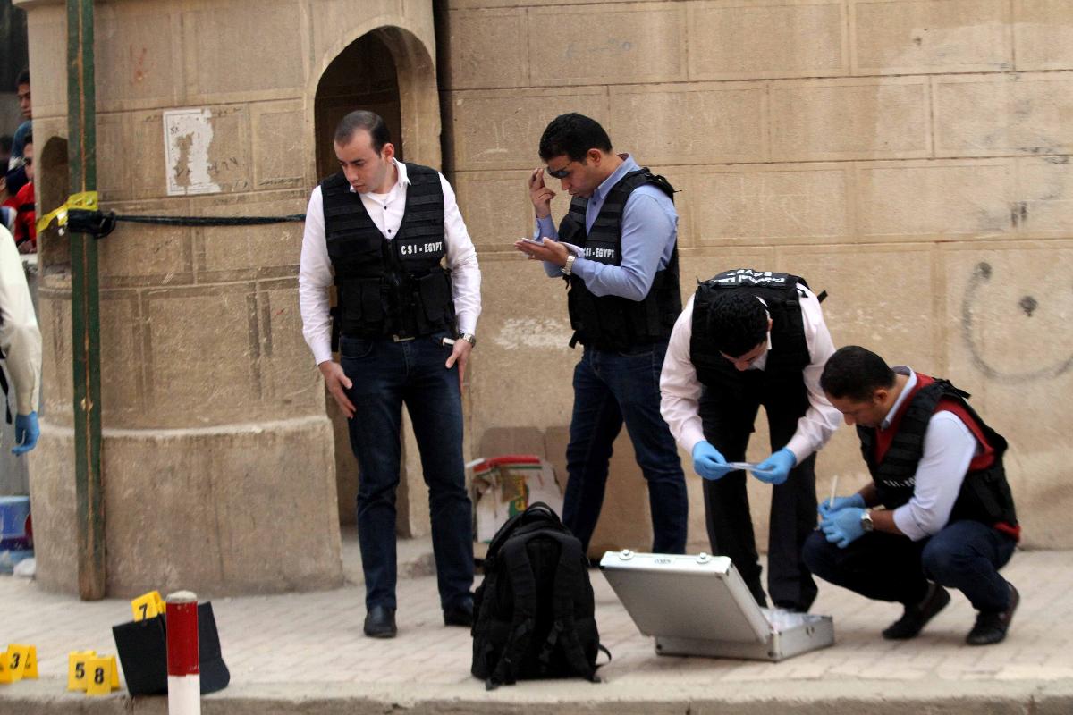 Membros da Segurança e da polícia forense do Egito inspecionam a àrea onde ocorreu o ataque armado,  do lado de fora de uma igreja no sul de Cairo. | STRINGERAFP