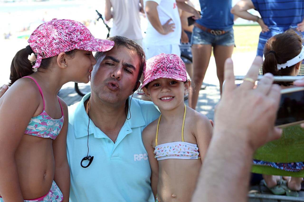 Pai tira foto das filhas com o jornalista Jasson Goulart na praia em Guaratuba: carinho dos fãs é constante na temporada. | Albari Rosa /Gazeta do Povo
