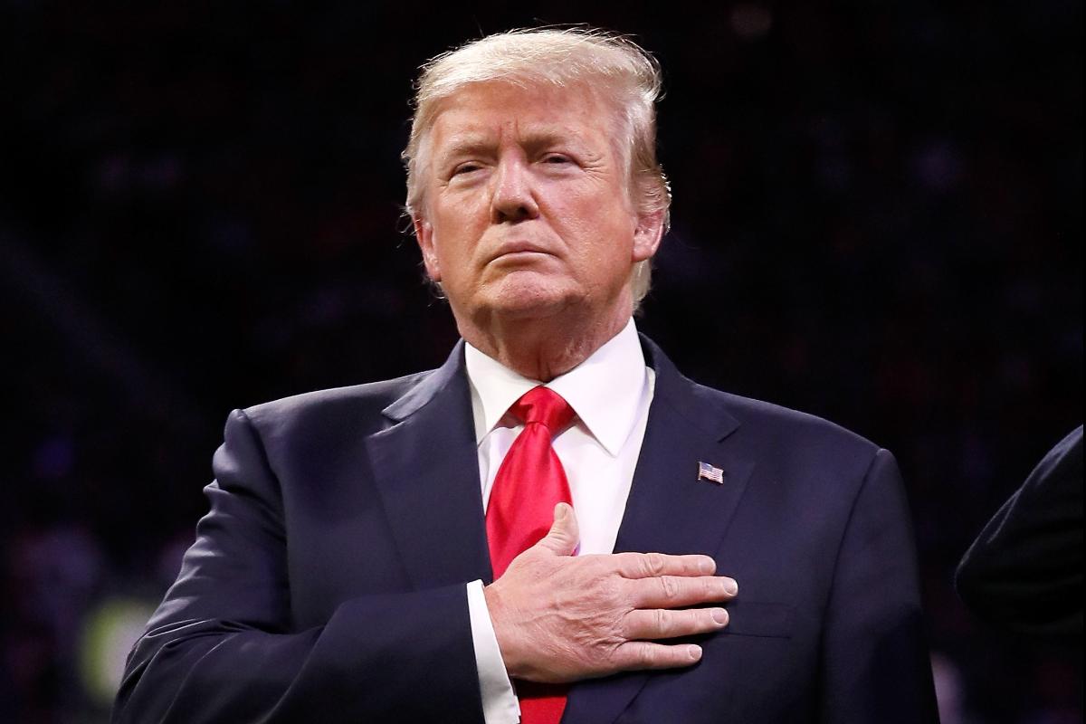 Presidente dos Estados Unidos, Donald Trump, durante a execução do hino nacional em um jogo de futebol em Alabama, nesta segunda-feira (8). | JAMIE SQUIREAFP