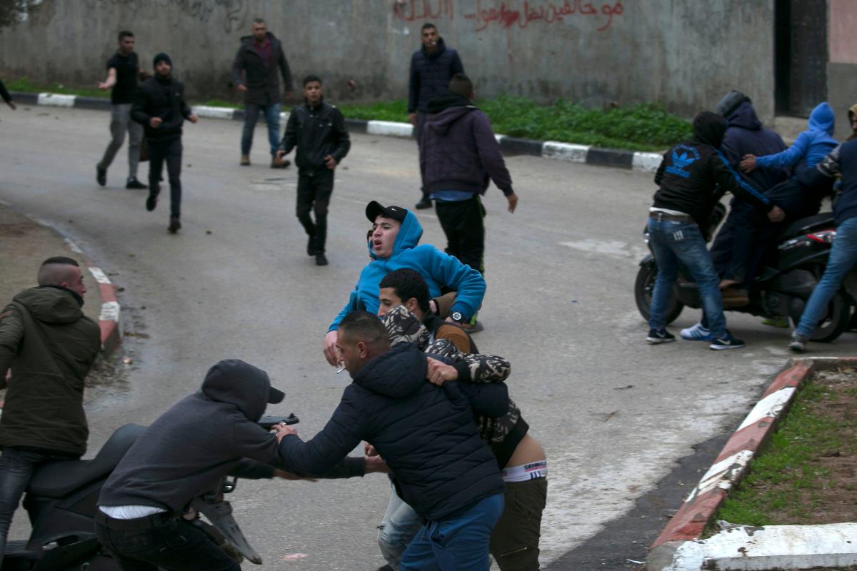 Jovens palestinos carregam um amigo ferido durante confrontos com forças israelenses em Jenin | JAAFAR ASHTIYEH/AFP