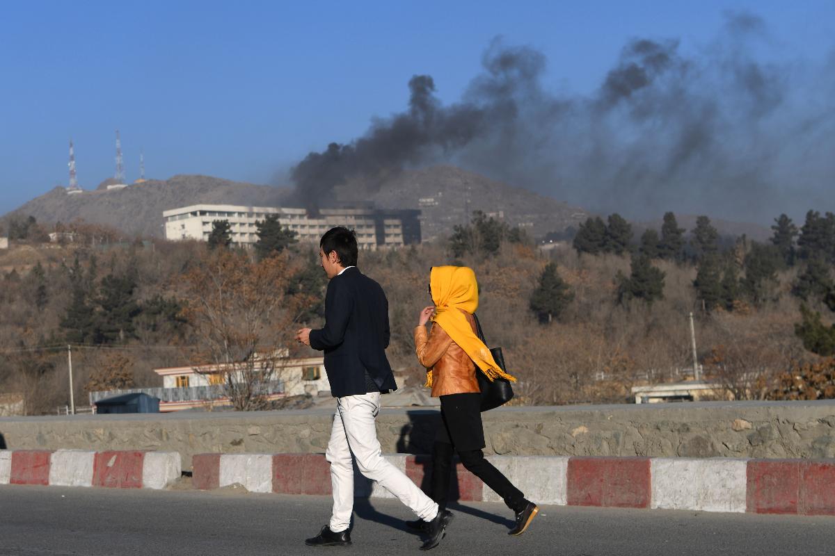 Afegãos correm perto do Hotel Intercontinental em Cabul, alvo de ataque do grupo Taleban | WAKIL KOHSAR/AFP