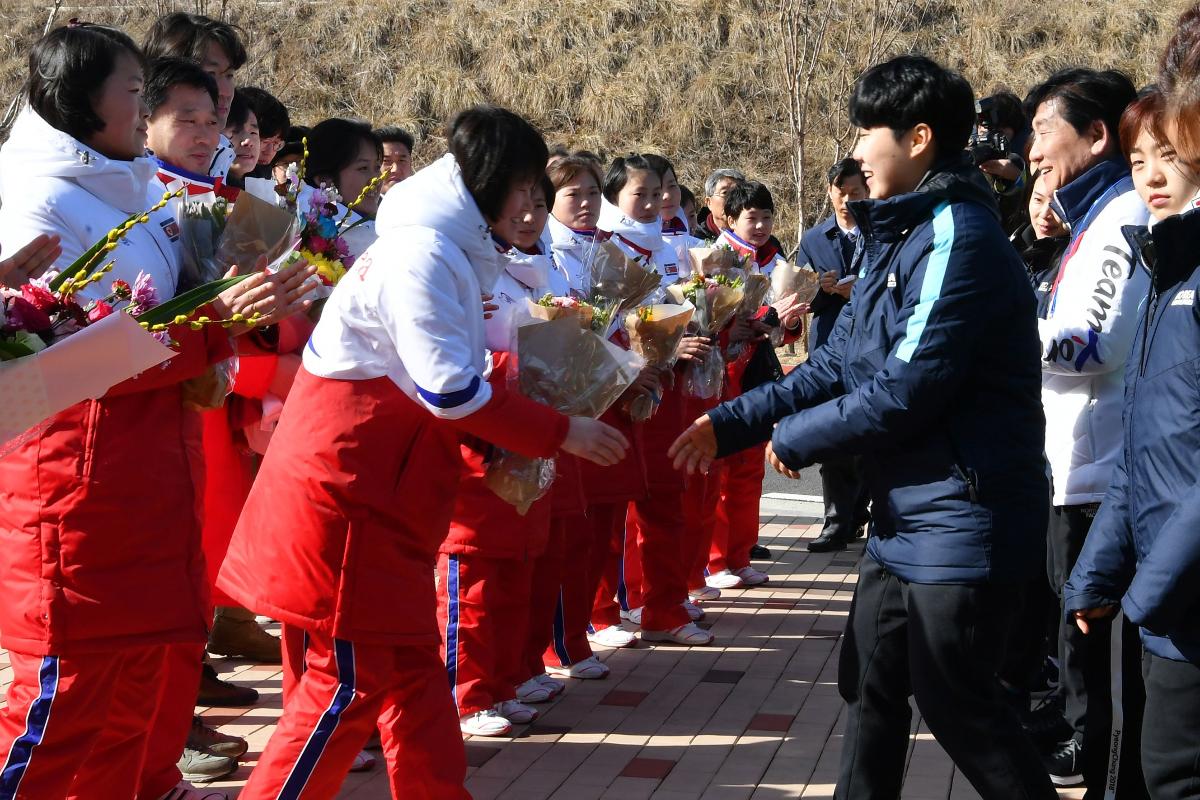 Membros da equipe de hóquei de gelo da Coréia do Norte (em branco e vermelho) são recebidos pelos membros da equipe sul-coreana (em azul) | SONG KYUNG-SEOK/
AFP