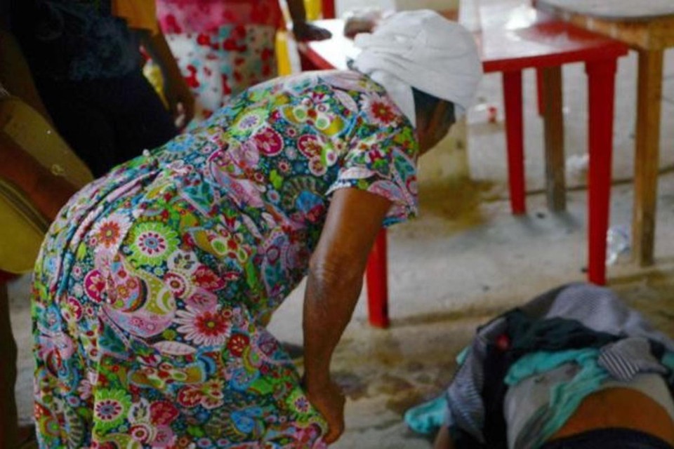 Um mulher olha para uma das vítimas fatais depois de um tiroteio na vila de La Concepcion, em Acapulco, México. | FRANCISCO ROBLESAFP PHOTO