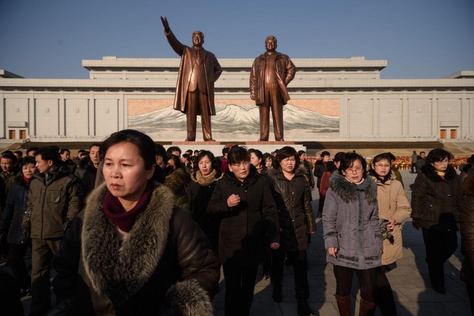 Moradores de Pyongyang  e as estátuas de Kim Il Sung (à esq.) e Kim Jong Il (à dir.) durante as festividades que marcam o 76º aniversário do nascimento do líder norte-coreano Kim Jong Il | KIM WON-JIN/AFP
