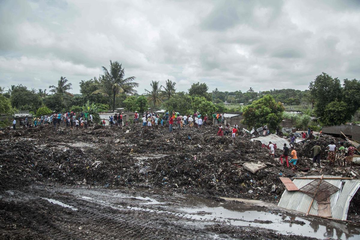 Moradores ficam sobre o monte de lixou que colapsou sobre as casas, no distrito de Maputo, em Moçambique | MAURO VOMBE/AFP