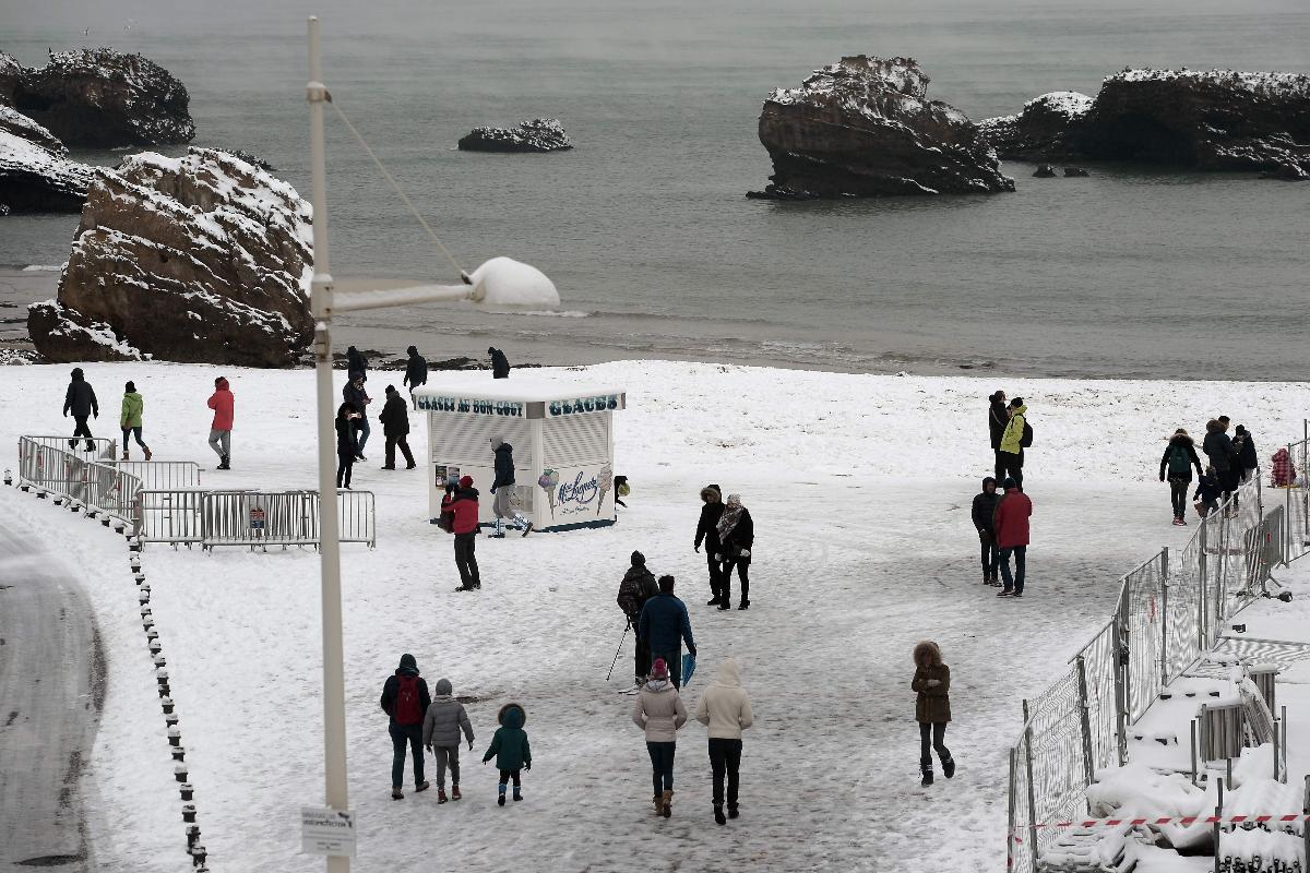 Pessoas caminham sobre a neve que cobriu a Grande Praia, a principal praia de Biarritz, no sudoeste da França | IROZ GAIZKA/AFP