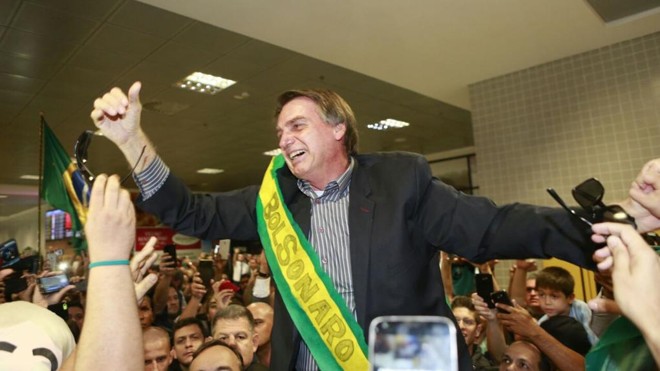 Bolsonaro ganhou uma espécie de “faixa presidencial” dos apoiadores que o aguardavam no saguão do Afonso Pena. | Marcelo Andrade/Gazeta do Povo