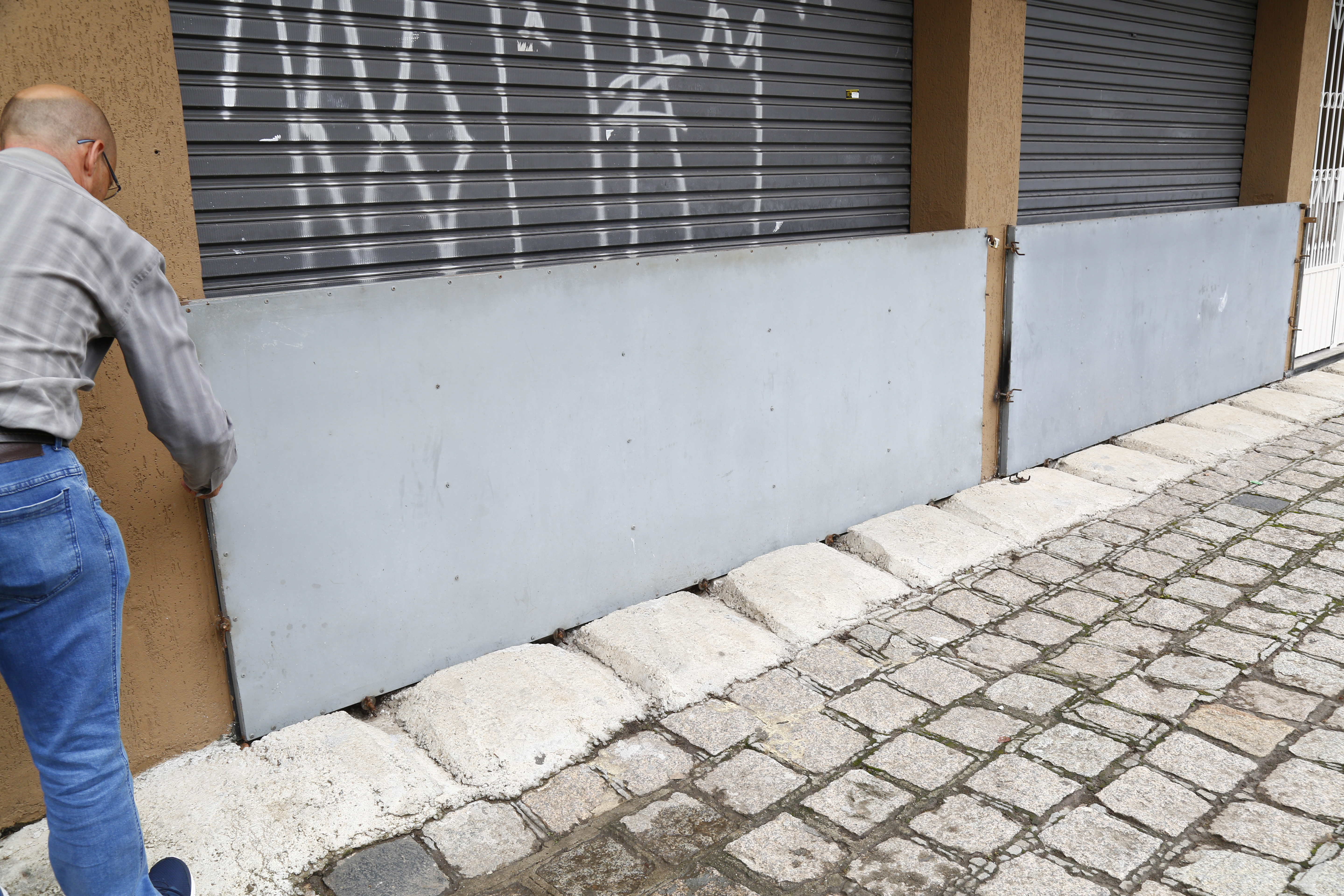 Barreira para tentar conter  água em comércio da Rua Almirante Gonçalves: há quase 20 anos endereço sofre com enchentes. | Aniele Nascimento/Gazeta do Povo