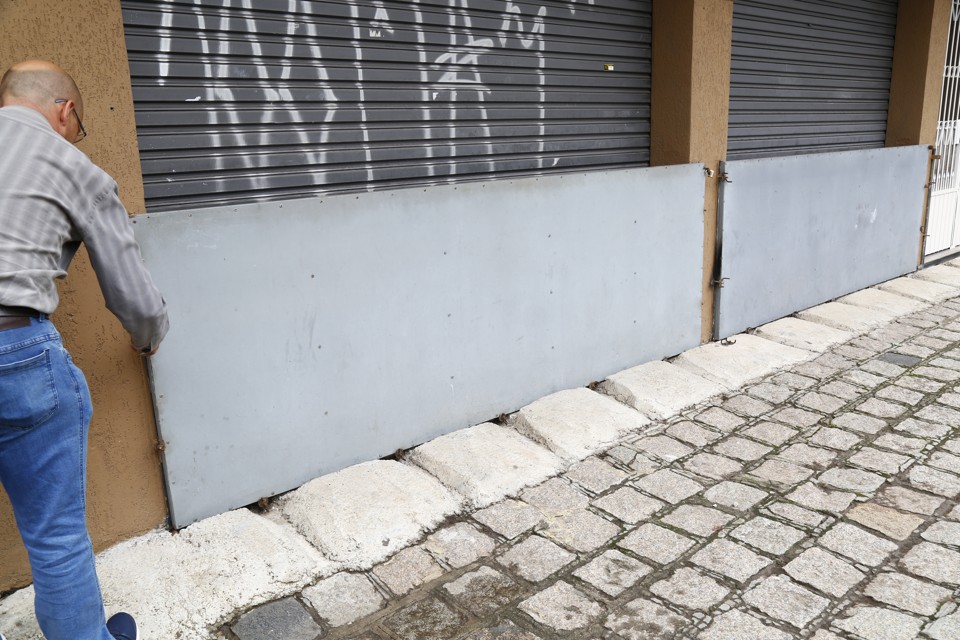 Barreira para tentar conter  água em comércio da Rua Almirante Gonçalves: há quase 20 anos endereço sofre com enchentes. | Aniele Nascimento/Gazeta do Povo