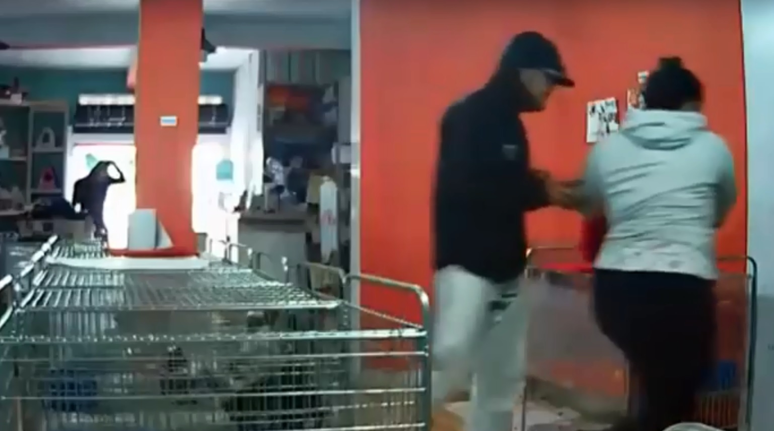 Os dois assaltantes, um deles à frente, rendendo uma funcionária da loja ,e outro ao fundo, na porta do estabelecimento. | Reprodução/Vídeo