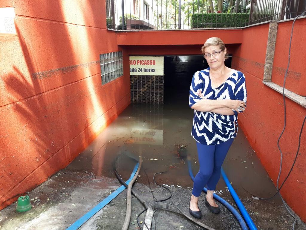 Moradora Letícia Monte Serrat Titton na frente da garagem cheia de água nesta quinta: desde 1999 Rua Fernando Amaro não tinha alagamento dessa proporção. | Alex Silveira/GAzeta do Povo
