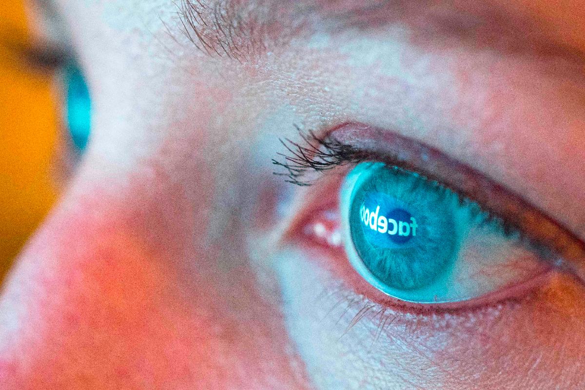 Logo do Facebook refletido no olho de uma mulher. | Josh Edelson/AFP