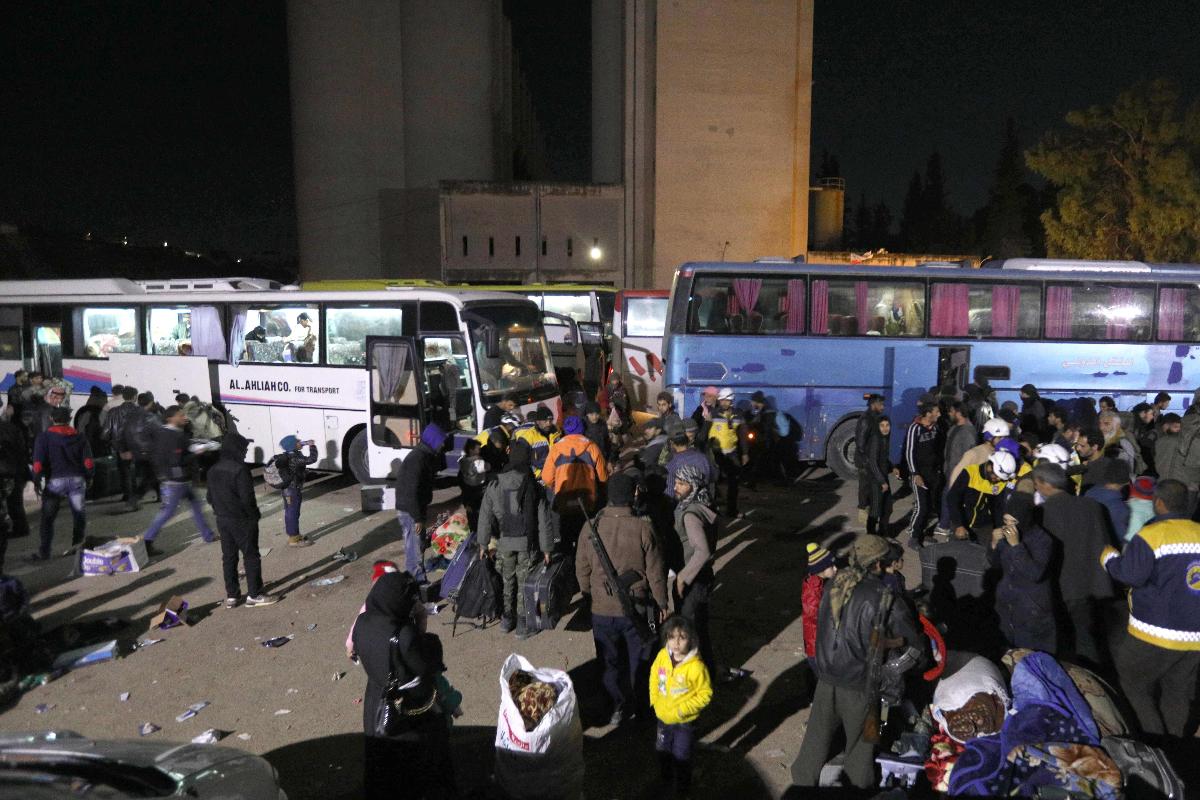 Civis e rebeldes sírios deixam a região de Guta Oriental com destino a Qalaat al-Madiq, a cerca de 45 quilômetros a noroeste da cidade de Hama | OMAR HAJ KADOUR/AFP
