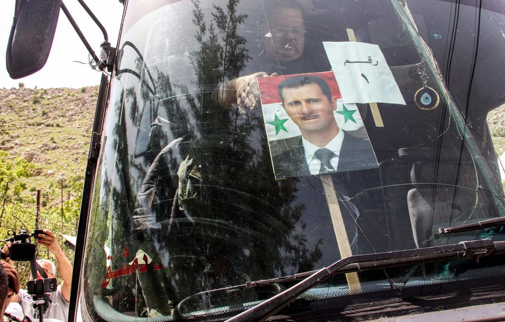 Homem fixa um cartaz de apoio ao ditador sírio Bashar Al-Assad: ações polêmicas | ALI DIA/AFP