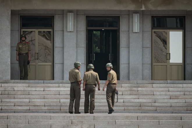 Soldados norte-coreanos caminham em frente ao Pavilhão Panmon, no lado norte da aldeia de Panmunjom, que separa a Coreia do Norte e a do Sul | ED JONES/
AFP