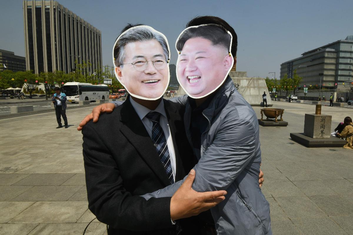 Sul-coreanos usam máscaras do presidente sul-coreano, Moon Jae-in (à esquerda), e do líder norte-coreano, Kim Jong-un (à direita), durante um manifesto para apoiar a cúpula inter-coreana | JUNG YEON-JE/
AFP