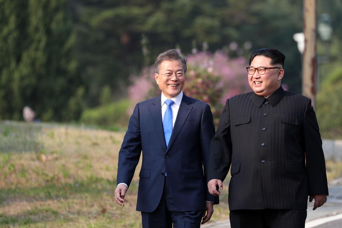 O líder da Coreia do Norte, Kim Jong-un e o presidente da Coreia do Sul, Moon Jae-in, caminham juntos após uma cerimônia de plantio de árvores na aldeia de Panmunjom, em 27 de abril de 2018. | KOREA SUMMIT PRESS POOL/AFP