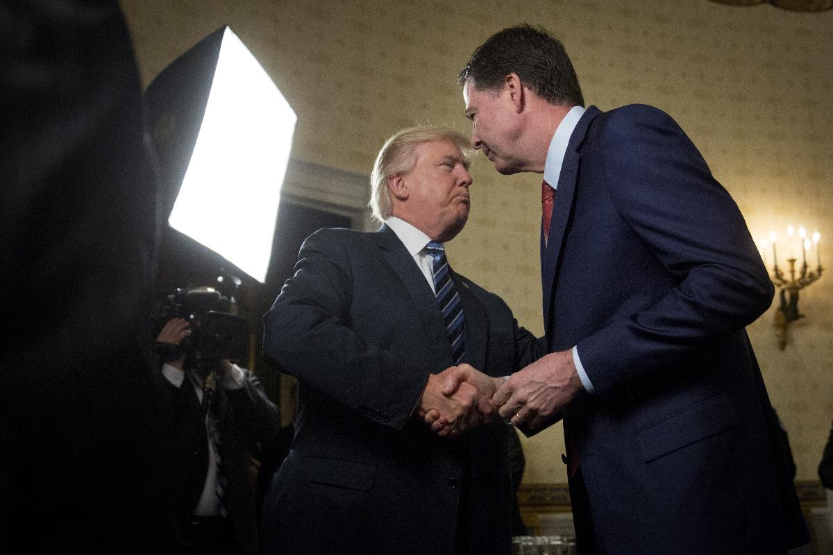 O presidente Donald Trump (à esquerda) aperta a mão de James Comey, então diretor do FB I, no Salão Azul da Casa Branca, em Washington, em 22 de janeiro de 2017. | Andrew Harrer/Bloomberg