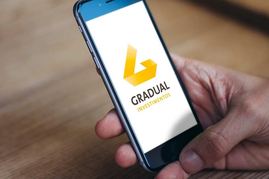 Celular com logo da Gradual Investimentos na tela. | Gradual/Reprodução