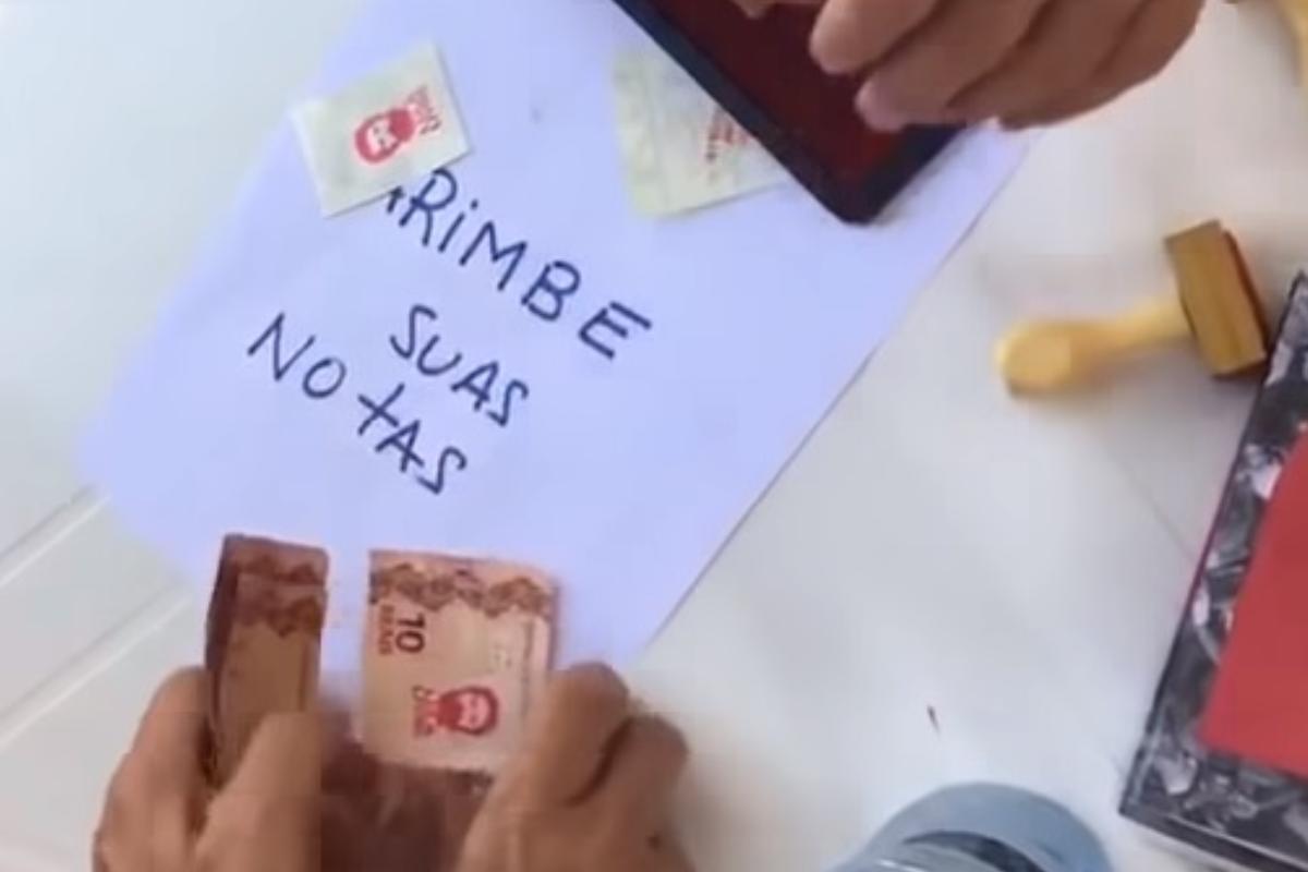 Simpatizantes do ex-presidente Lula carimbam rosto do petista em cédulas de dinheiro.  | Reprodução/
YouTube