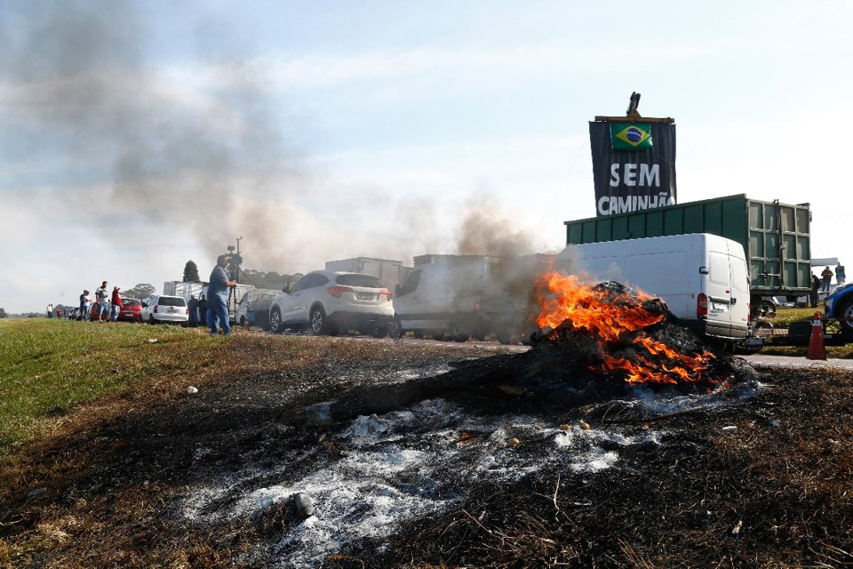 Manifenstantes em um trecho da Av Juscelino Kubitschek , em Curitiba, queimando pneus e segurando caminhões e veículos pequenos carregados | Aniele Nascimento/Gazeta do Povo