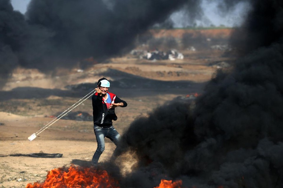 Jovem palestino arremessa uma pedra durante confrontos com forças israelenses na terça-feira (15), perto da fronteira com Israel | MOHAMMED ABEDAFP