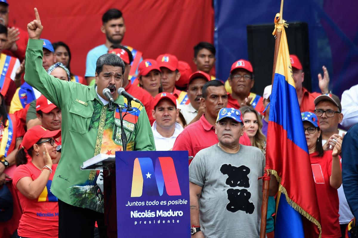 O ditador venezuelano, Nicolas Maduro, fala ao público ao lado do ex-jogador de futebol Diego Maradona, durante o comício de encerramento de sua campanha, em Caracas | JUAN BARRETOAFP
