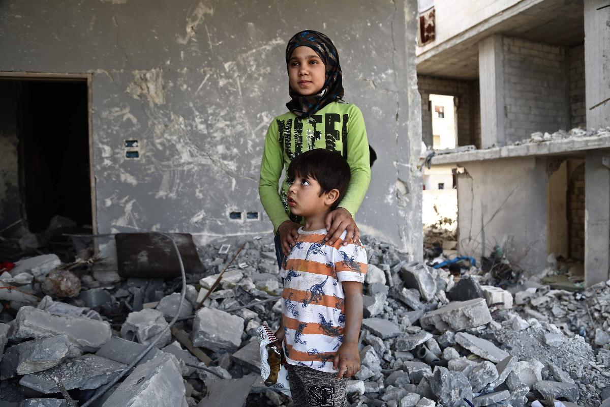 A menina síria Inas Haymur e seu irmão Saad (abaixo) posam para uma foto em Afrin, no dia 26 de maio de 2018. Deslocados de suas casas na região oriental de Ghouta, na Síria, famílias buscaram refúgio em casas abandonadas na cidade tradicionalmente curda de Afrin. | NAZEER AL-KHATIB/AFP