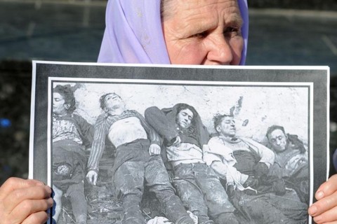 Mulher segura retrato com imagens de pessoas mortas durante o regime de Joseph Stalin | AFP PHOTO / YURIY DYACHYSHYN