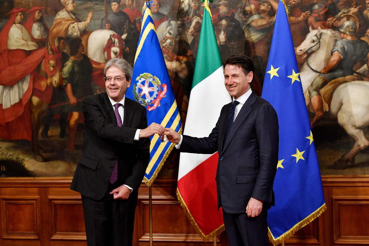 O novo premiê da Itália, Giuseppe Conte (à direita), recebe um sino de prata do premiê anterior, Paolo Gentiloni, em cerimônia. Conte tomou posse nesta sexta-feira (1), após meses de impasse. | ANDREAS SOLARO/AFP