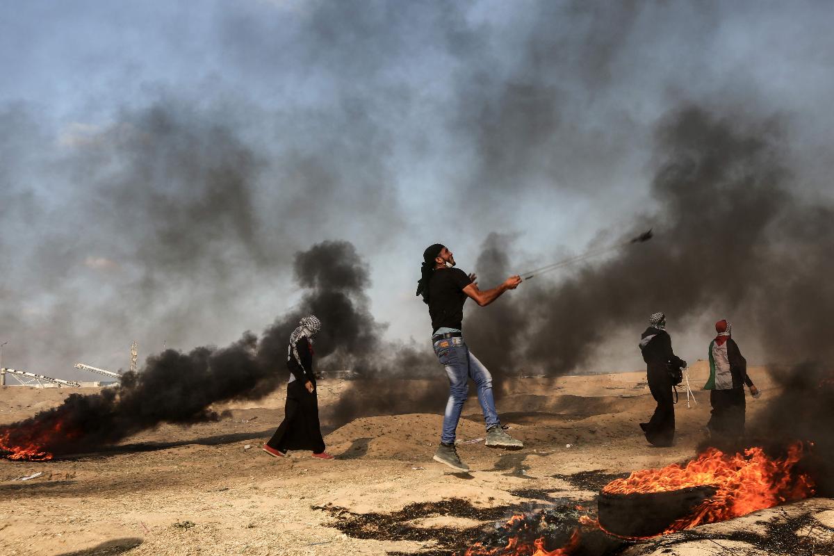 Palestino usa estilingue para atingir tropas israelenses, durante protesto na Faixa de Gaza | MAHMUD HAMS/AFP