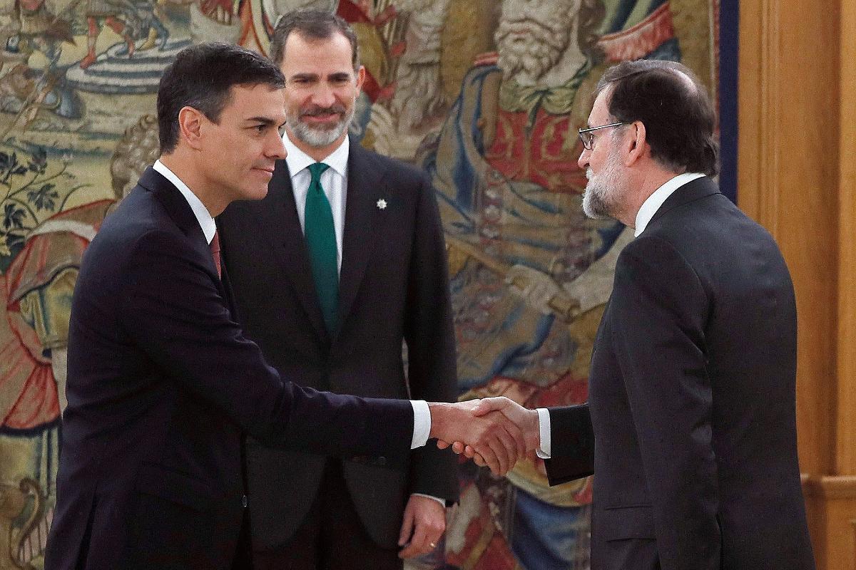 Sob o olhar de Felipe 6° (C), rei espanhol, o novo primeiro ministro, Pedro Sanchez (E), cumprimenta Mariano Rajoy, seu antecessor | FERNANDO ALVARADO/AFP