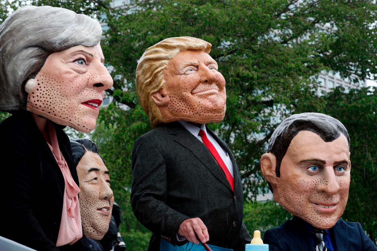 Manifestantes usam máscaras de líderes do G7: Theresa May, do Reino Unido; Shinzo Abe, do Japão; Donald Trump, dos EUA; e Emmanuel Macron, da França | LARS HAGBERGAFP