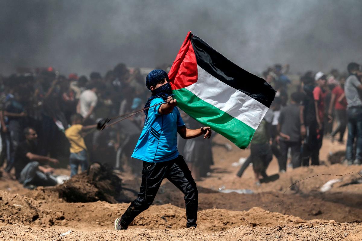 Manifestante palestino segura bandeira durante protesto na fronteira entre Israel e Gaza | MOHAMMED ABED/AFP