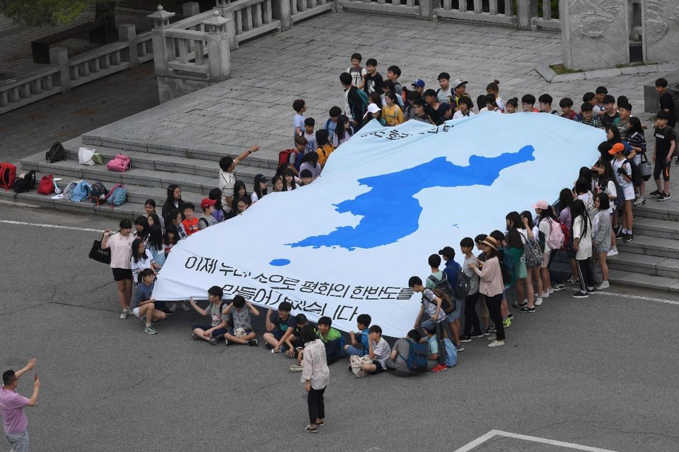 Perto da zona desmilitarizada entre as Coreias, estudantes exibem uma bandeira gigante com o mapa das Coreias unificadas e com a frase “nós vamos tornar a península coreana pacífica com nossas próprias mãos” | JUNG YEON-JE
AFP