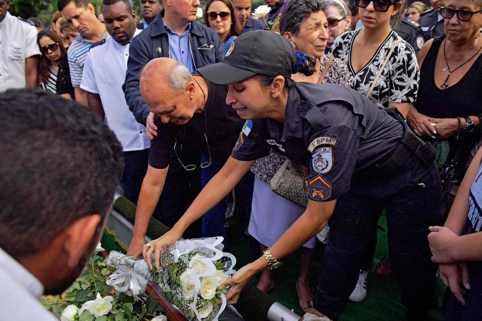 Uma policial coloca flores no túmulo do coronel da polícia Luis Gustavo Teixeira, durante seu funeral em Sule Cap, no oeste do Rio de Janeiro, Brasil, em 27 de outubro de 2017, um dia depois de ser morto a tiros em uma favela. Teixeira era comandante do 3º Batalhão de Polícia Militar do Rio de Janeiro. Seu carro foi atingido por pelo menos 17 balas quando criminosos abriram fogo contra ele no Meier, bairro no norte do Rio de Janeiro. | CARL DE SOUZA/AFP