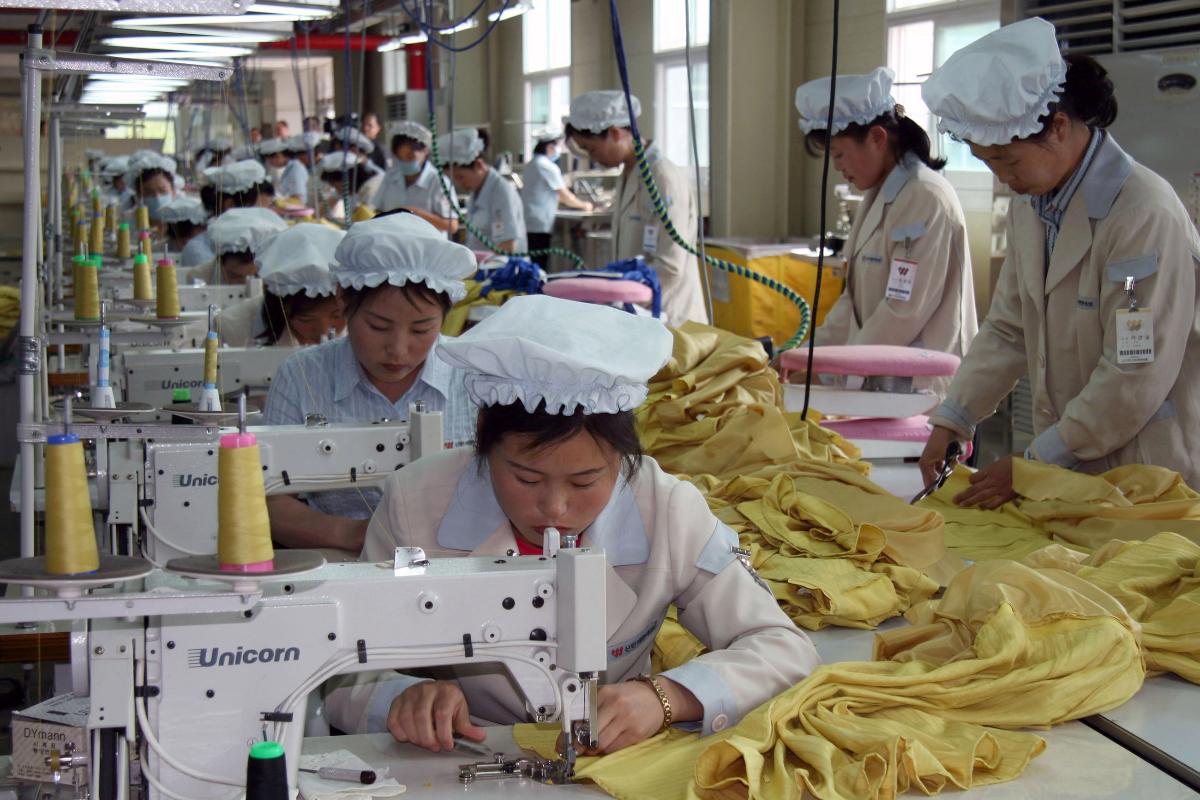 Trabalhadores norte-coreanos costuram roupa no complexo industrial de Gaeseong, que foi fechado em 2016 | HEEJIN KOO/Bloomberg