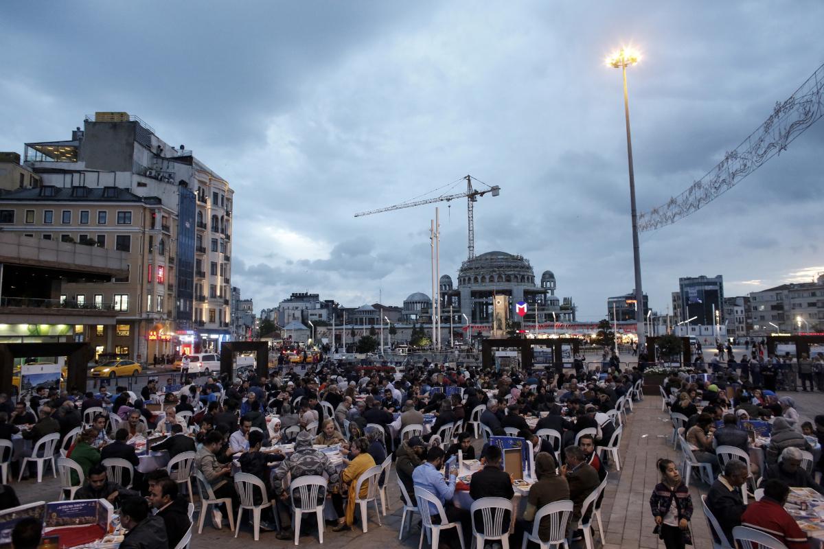 Pessoas participam da janta Iftar, a refeição que tradicionalmente encerra o jejum diário dos muçulmanos, na praça Taksim, em Istanbul | Kostas Tsironis/Bloomberg